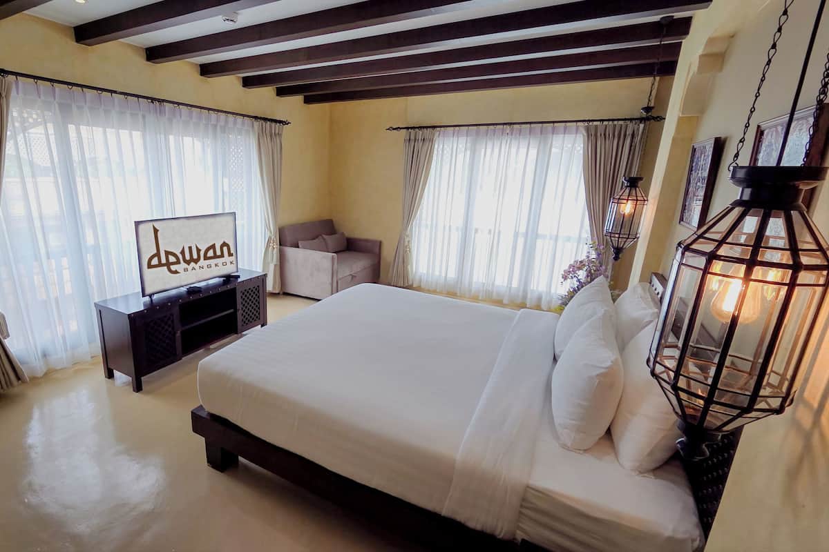 A bedroom with a bed, a sofa, a TV, and curtains.
