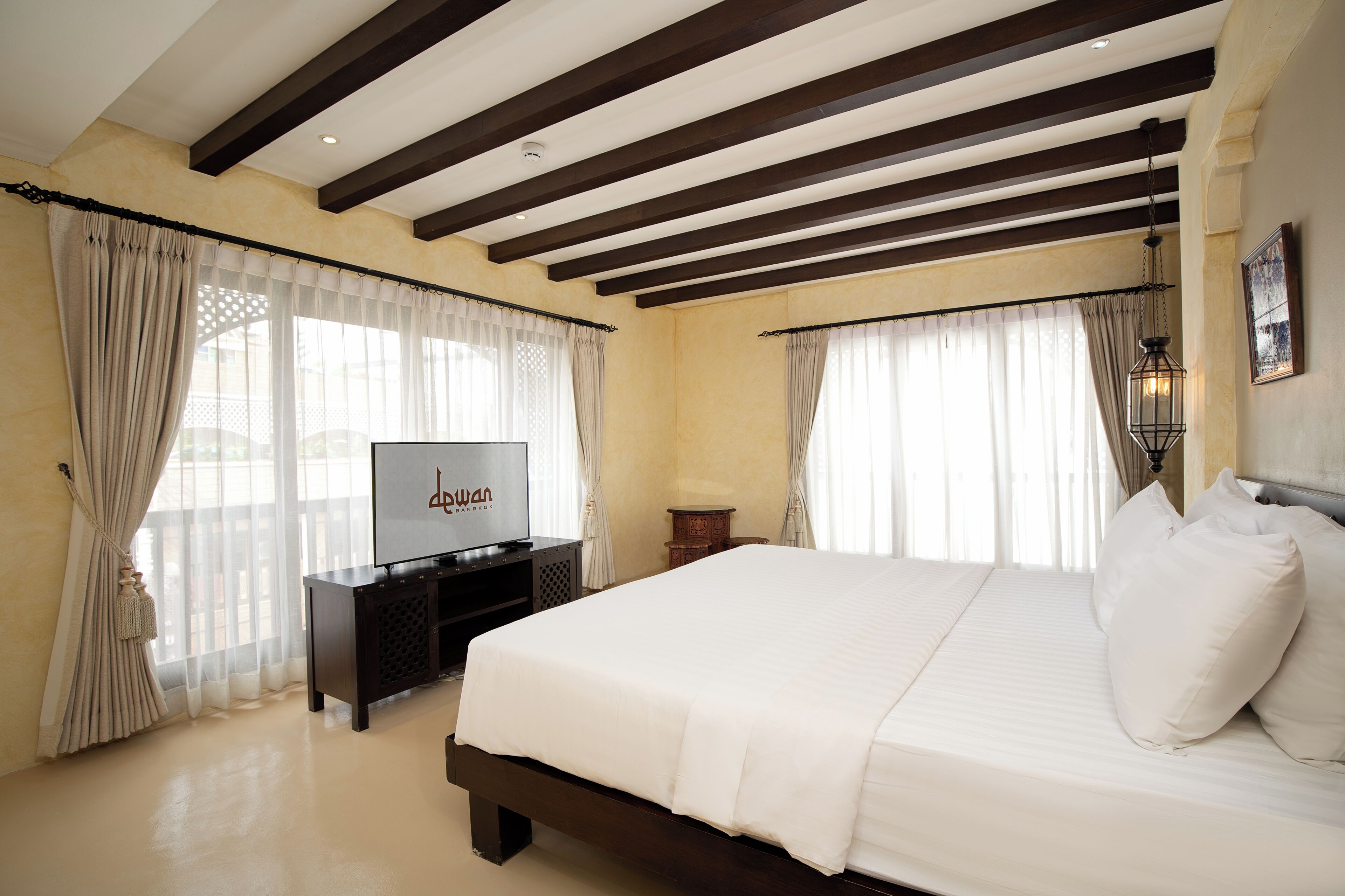 A bedroom with a bed, a TV, and a wooden ceiling.