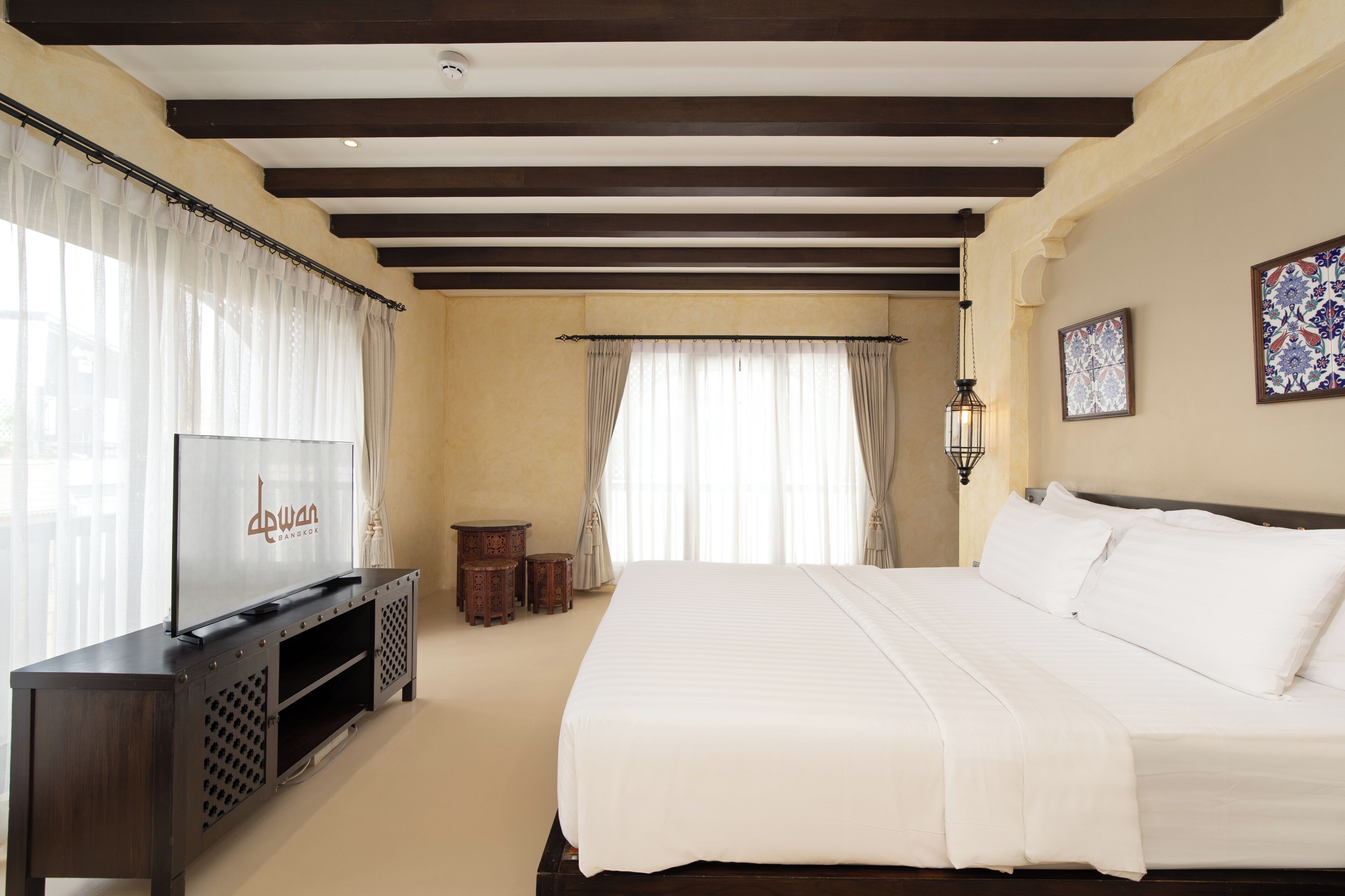 Un dormitorio con cama, televisor, una mesita y un adorno en la pared.