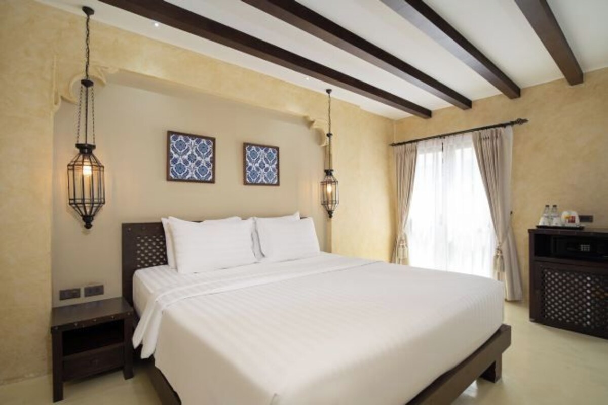 Une chambre à coucher avec un grand lit, deux lampes fixées au mur et une table de chevet.