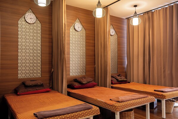 Habitación con tres camas, cada una con ropa de cama y almohadas estampadas, paneles de madera y un espejo grande.