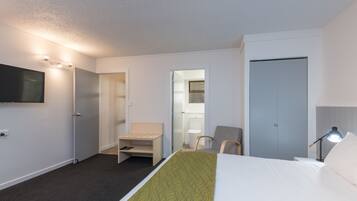 A hotel room with a bed, a desk, a chair, a TV, and a wardrobe.