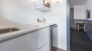 A modern kitchen with a built-in microwave, a sink, and a dishwasher. There is a small table and chairs in the adjacent room.