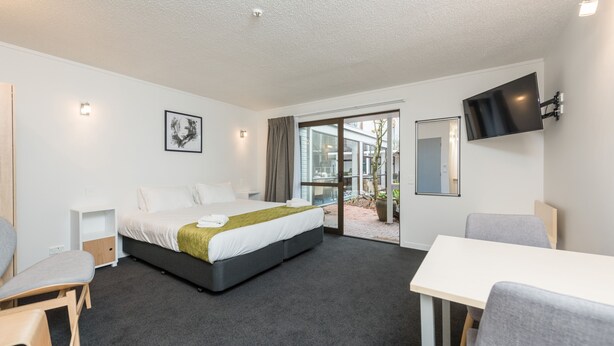 A modern hotel room with a large bed, a desk, and a TV.