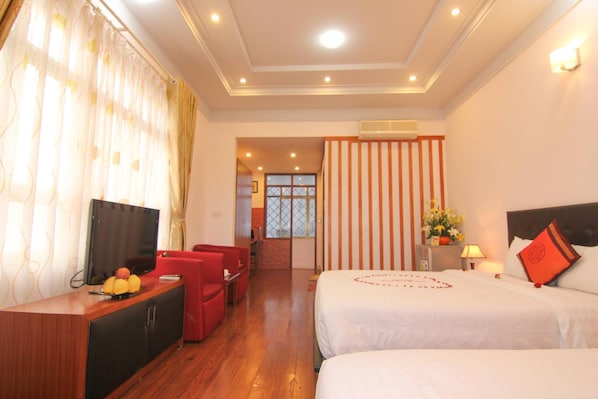 A hotel room with two beds, a TV, a desk, and a red chair.