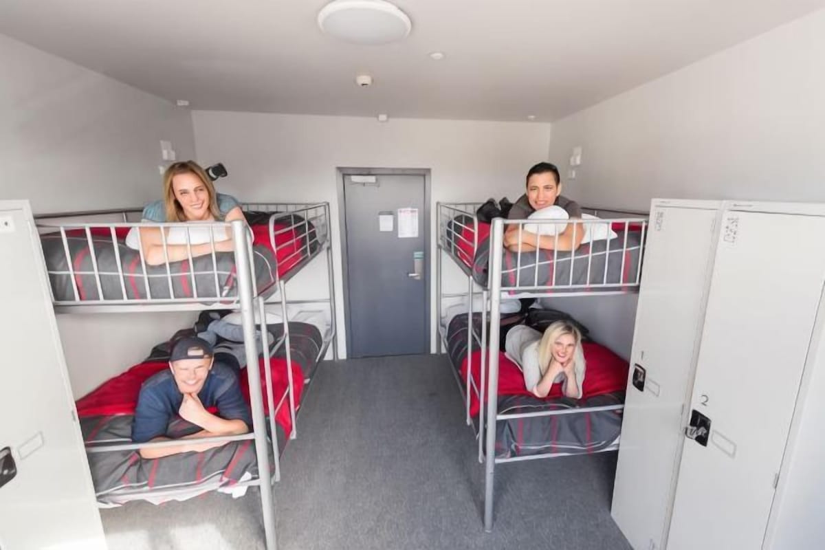A dormitory room with bunk beds, a door, and lockers.