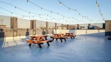A rooftop terrace with picnic tables and string lights.