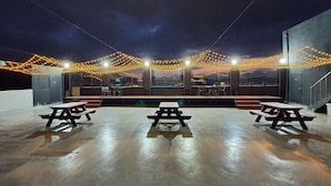An outdoor patio area with picnic tables and string lights.