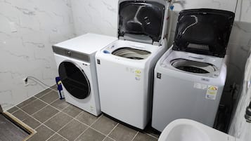 A laundry room with three stacked washing machines, a sink, and a toilet.
