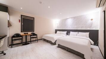 A hotel room with two beds, a desk, chairs, and a marble wall.