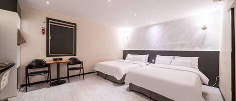 A hotel room with two beds, a desk, chairs, and a marble wall.