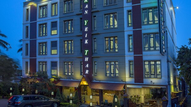 Un hotel de varios pisos con un letrero llamativo que dice "HOTEL KANYEKTHAR" y una entrada bien iluminada.