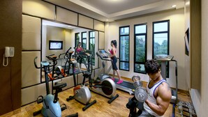 Un gimnasio con equipo de ejercicio, una cinta de correr y un banco para pesas.