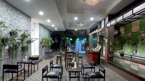 Un restaurante con una decoración moderna, que incluye una zona de bar, mesas y plantas decorativas.
