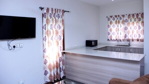 Een moderne keuken met een flatscreen-televisie, een magnetron en een spoelbak.