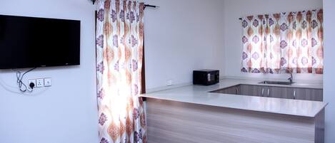 Una cocina moderna con televisor de pantalla plana, microondas y pileta.