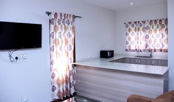 A modern kitchen with a flat-screen TV, a microwave, and a sink.