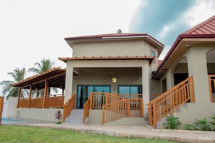 A building with a covered entrance, wooden stairs, and a pool area.