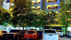 A multi-story hotel with illuminated signage and a parking lot in front. - 14 Avenue (Bangkok)