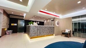 A modern reception area with a marble counter, a clock, and a seating area with a blue sofa. - 14 Avenue (Bangkok)