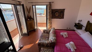 Un dormitorio con una cama grande, un sofá, vista al mar y un balcón.