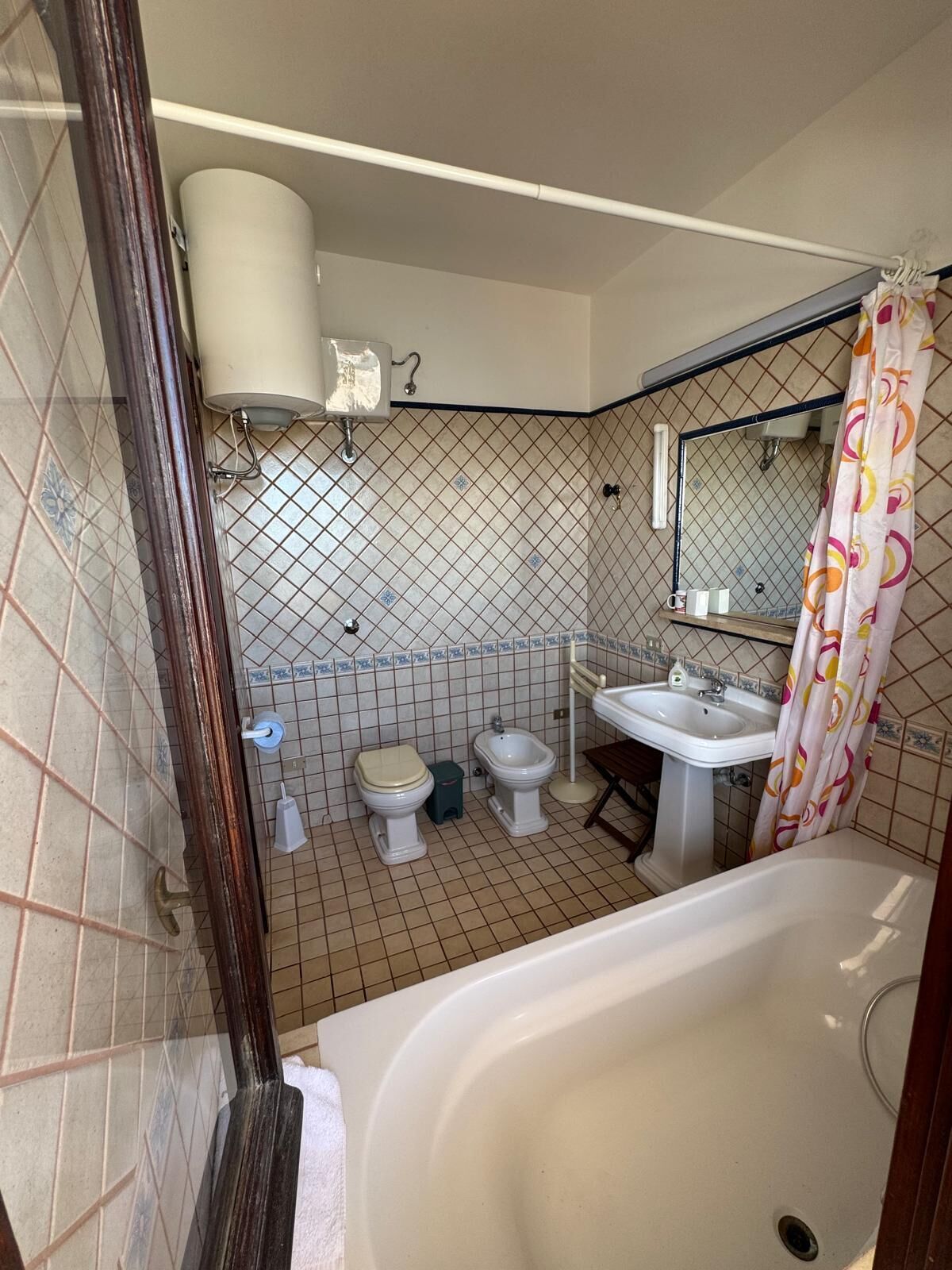 Un baño con bañera, dos inodoros, un lavabo y cortina de ducha.