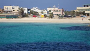 Vista costera con edificios, una playa de arena y mar tranquilo.