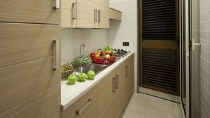 A kitchen with wooden cabinets, a stainless steel sink, and a fruit basket on the counter. - Residence Blu ModicAmare (Modica)