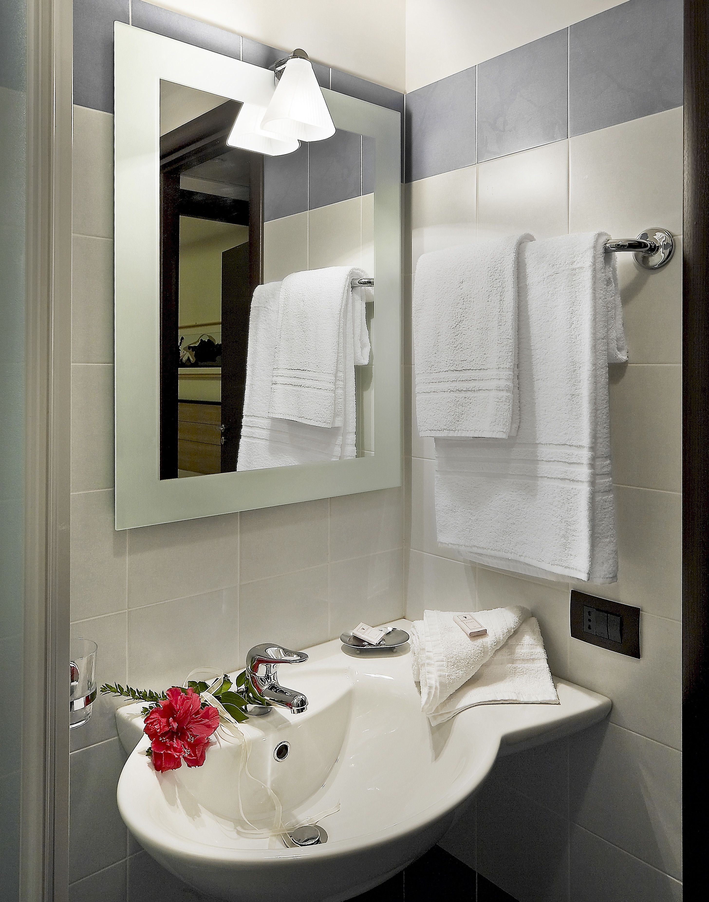 A bathroom with a white sink, a mirror, and two towels hanging on a rack.