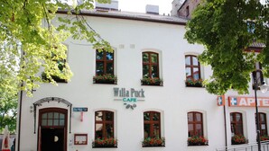 En hvid bygning med skiltet "Willa Puck Cafe" og blomsterkasser ved vinduerne.