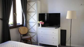 Quarto de hotel com uma cama, uma televisão em uma cômoda, uma cadeira e um abajur.