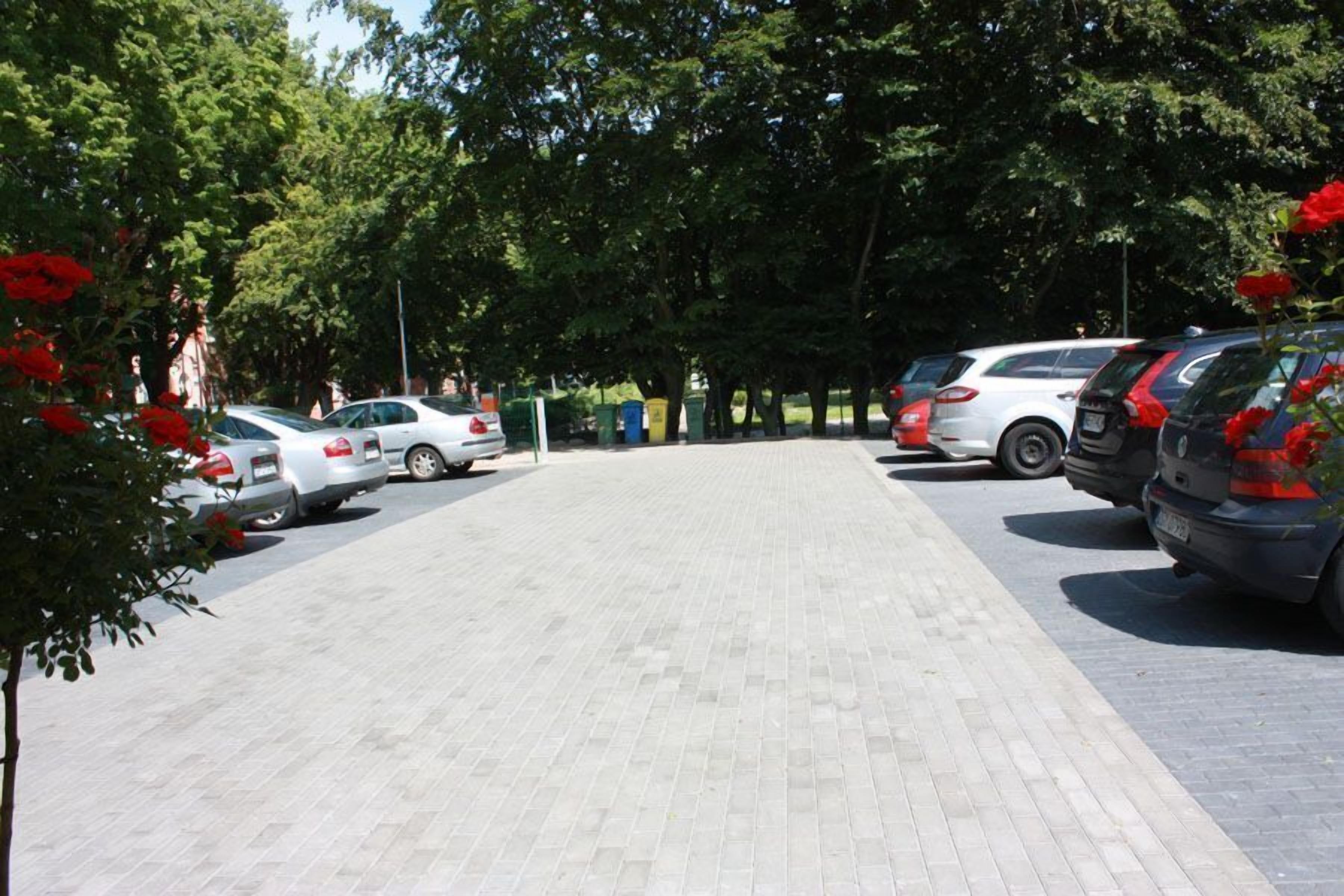 A parking area with several cars parked, surrounded by trees and greenery.