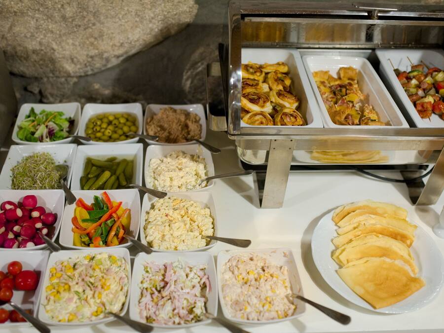 Un buffet con diverse opzioni tra cui insalate, salse e dolci.