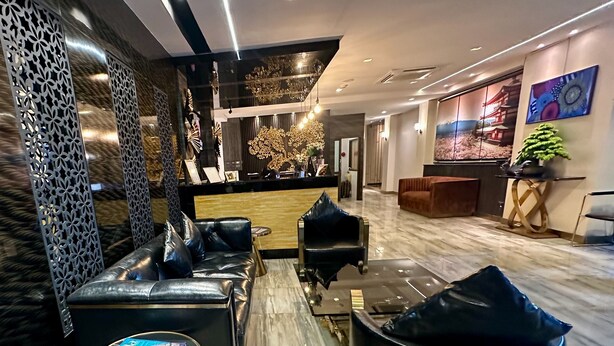 A modern lobby with leather seating, a reception desk, and decorative elements like a large painting and a tree sculpture. - Sakura Sky Residence (Bangkok)