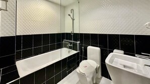 A modern bathroom with a large bathtub, a separate sink, and a toilet. - Sakura Sky Residence (Bangkok)