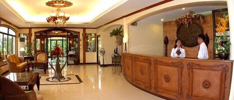 A spacious lobby with a reception desk, comfortable seating, and a chandelier.