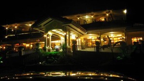 A large, illuminated building with multiple balconies and a reflective pool in front. - Camiguin Highland Resort (Mambajao)