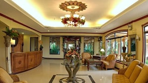 A spacious lobby with a central glass table, comfortable seating, and a decorative chandelier. - Camiguin Highland Resort (Mambajao)