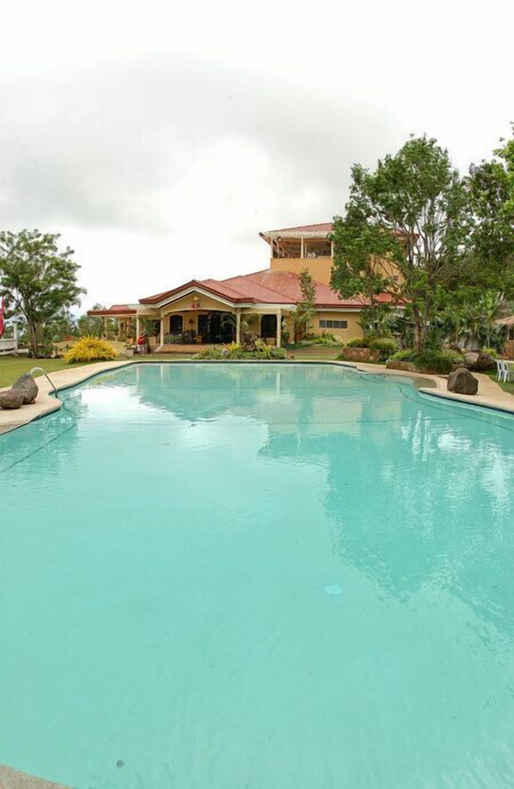 Piscina com uma casa ao fundo.