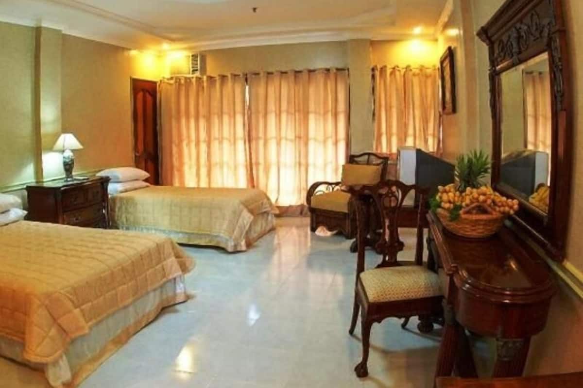 A hotel room with two beds, a desk with a computer, a chair, and a large mirror.