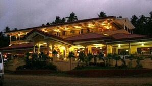 A large, multi-story hotel with a red roof and multiple balconies. - Camiguin Highland Resort (Mambajao)
