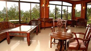 A spacious room with large windows, wooden furniture, and a view of palm trees. - Camiguin Highland Resort (Mambajao)