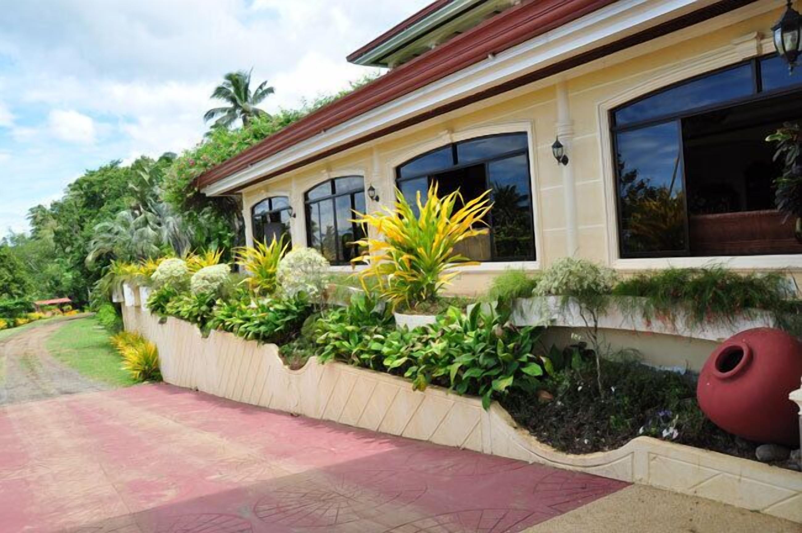 A house with a garden in front, a red pathway, and a large window.