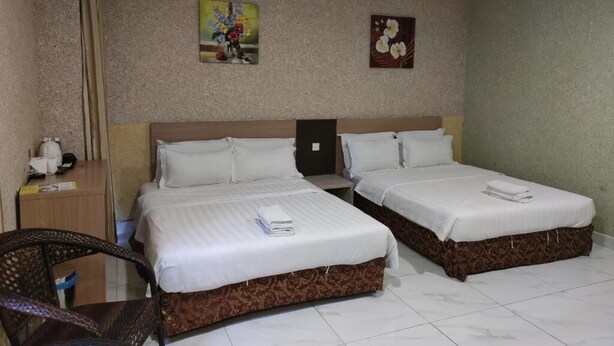 Ein Hotelzimmer mit zwei Betten, einem Schreibtisch, einem Stuhl und einem Deckenventilator.