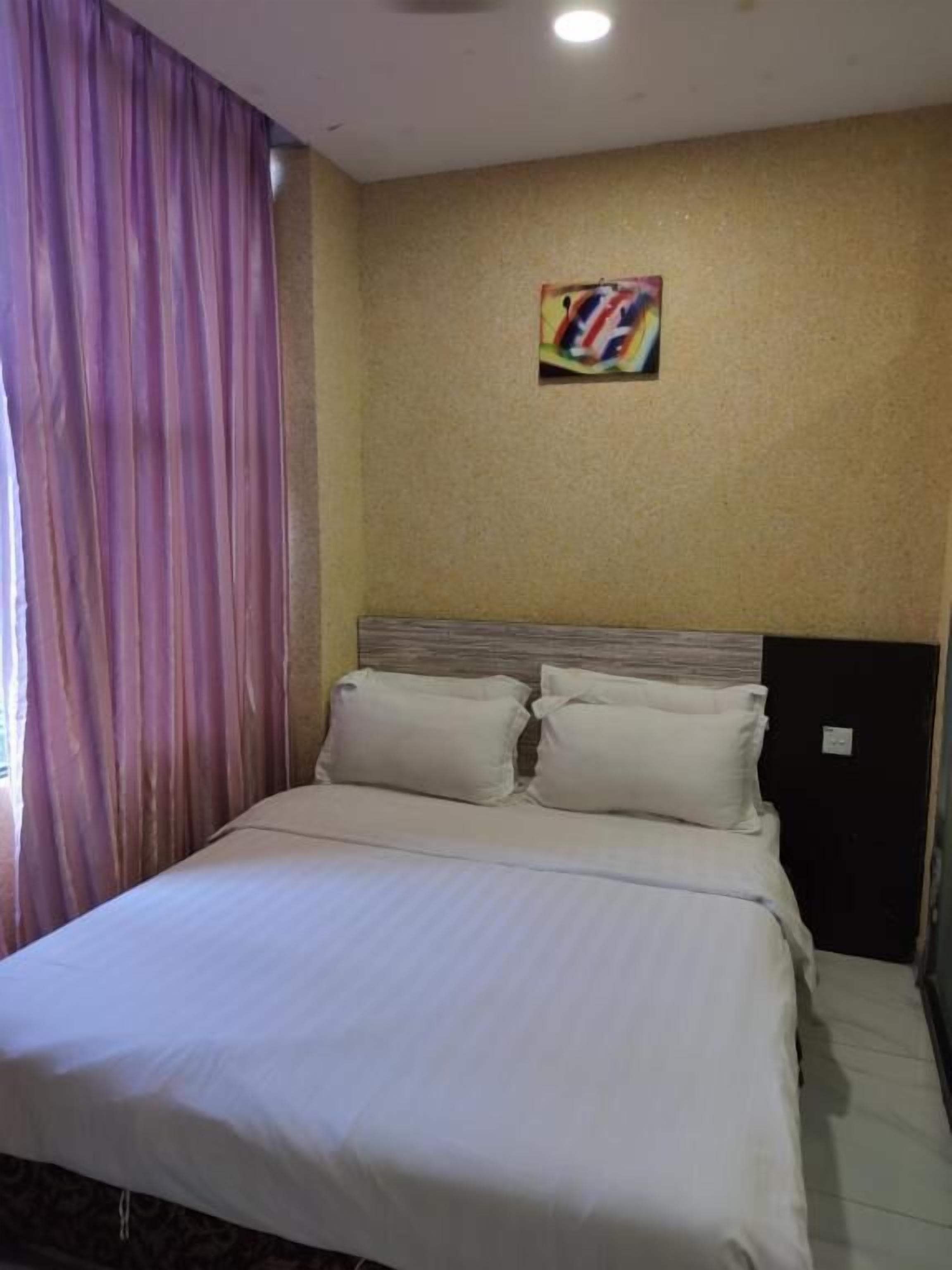 A hotel room with a large bed, a headboard, and a painting on the wall.