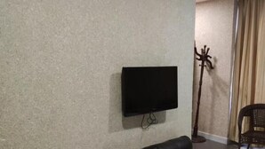 Ein Wohnzimmer mit einem schwarzen Ledersofa, einem flachbildfernseher an der Wand und einer Stehlampe.