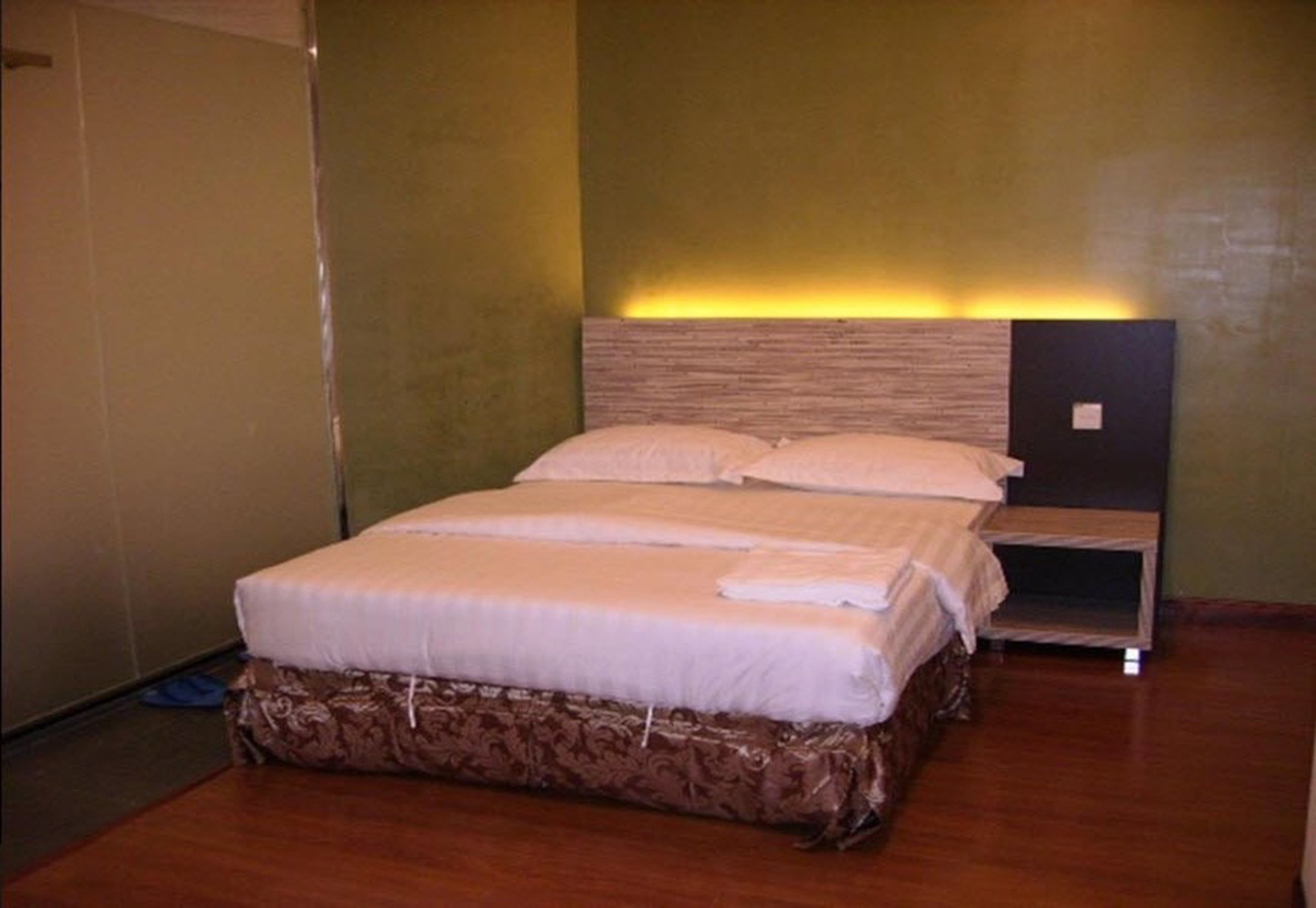 A neatly made bed with a wooden headboard and a bedside table.