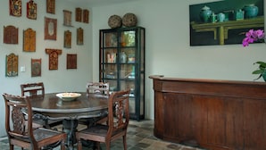 A dining area with a round wooden table surrounded by chairs, a cabinet with glass doors, and a painting on the wall. - Room & Vespa 3 (Seminyak)
