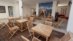 A spacious indoor area with wooden tables and chairs, a large mural on the wall, and a modern ceiling design. - RaBaSTa Mahayana Kuta (Kuta)