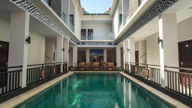 A large indoor swimming pool with a central seating area and a mural on the back wall. - RaBaSTa Mahayana Kuta (Kuta)
